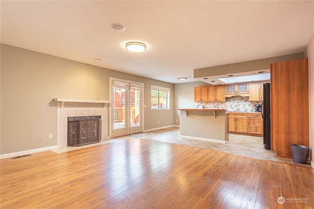 unfurnished living room featuring light hardwood / wood-style flooring and a tile fireplace