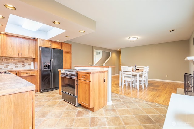 kitchen with decorative backsplash, light hardwood / wood-style floors, black appliances, and a kitchen island