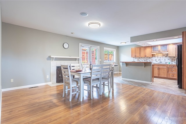 dining area with light hardwood / wood-style flooring, sink, and a tile fireplace