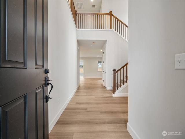 foyer entrance with a towering ceiling and light hardwood / wood-style floors