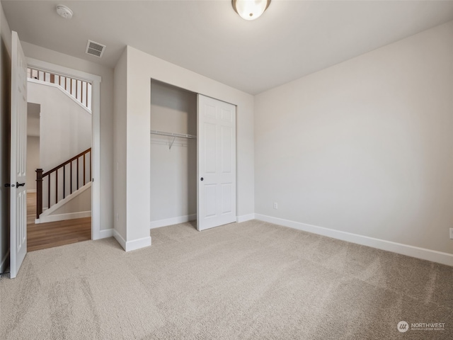 unfurnished bedroom featuring light colored carpet and a closet