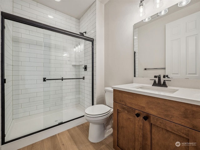 bathroom featuring toilet, an enclosed shower, hardwood / wood-style floors, and vanity