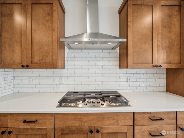 kitchen with stainless steel gas cooktop, wall chimney range hood, and backsplash