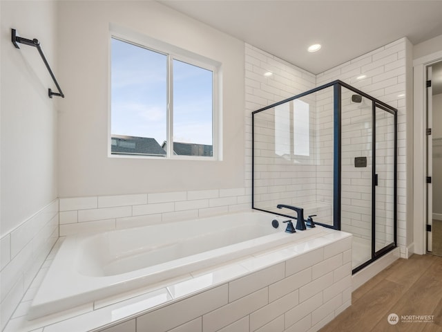 bathroom with hardwood / wood-style floors and shower with separate bathtub