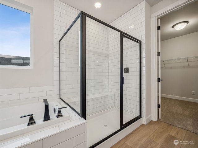 bathroom with independent shower and bath and wood-type flooring