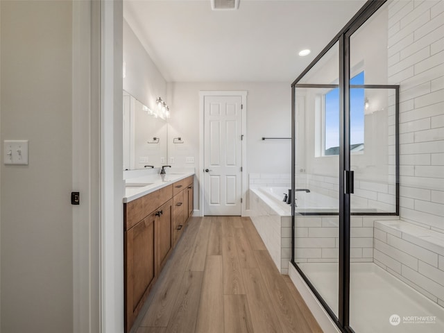 bathroom featuring vanity, wood-type flooring, and shower with separate bathtub