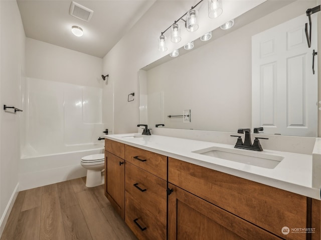 full bathroom with toilet, hardwood / wood-style floors, vanity, and shower / bathtub combination