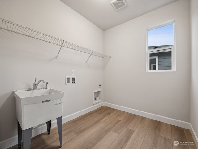 laundry room with hookup for a washing machine, electric dryer hookup, and light hardwood / wood-style flooring