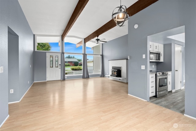 unfurnished living room featuring light hardwood / wood-style floors, beam ceiling, and ceiling fan