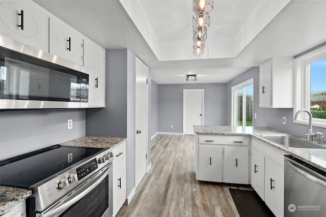 kitchen featuring wood-type flooring, sink, white cabinets, an inviting chandelier, and stainless steel appliances