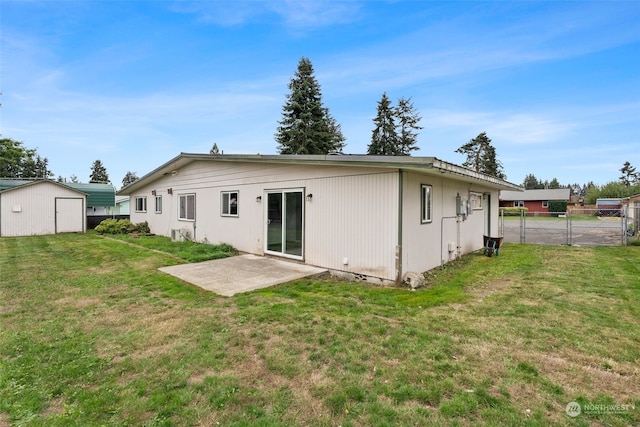 rear view of house with a lawn, a patio, and a shed