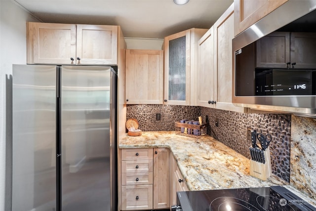 kitchen featuring light brown cabinets, tasteful backsplash, stainless steel appliances, and light stone countertops