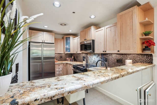 kitchen featuring appliances with stainless steel finishes, kitchen peninsula, light stone countertops, and light brown cabinetry