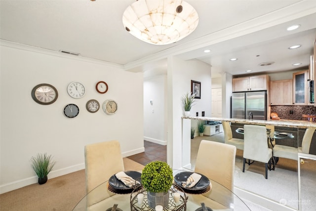 dining room with crown molding and light colored carpet