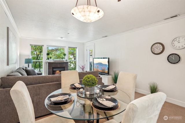 carpeted dining room featuring a tiled fireplace and crown molding