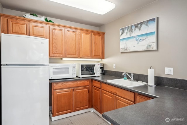 520 SE Columbia River Dr Unit 120, Vancouver, WA 98661 - kitchen with a sink, brown cabinetry, white appliances, and dark countertops