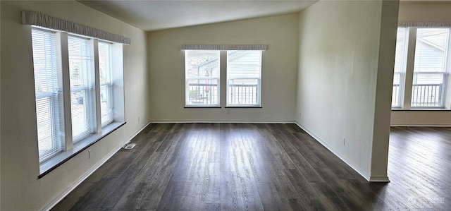 empty room with a wealth of natural light, vaulted ceiling, and dark hardwood / wood-style floors