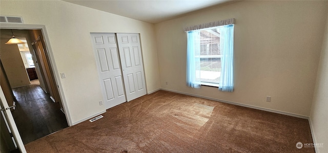 unfurnished bedroom featuring vaulted ceiling, a closet, dark colored carpet, and multiple windows