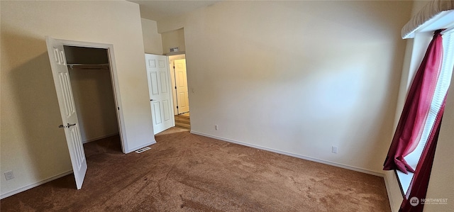 unfurnished bedroom featuring dark colored carpet and a closet