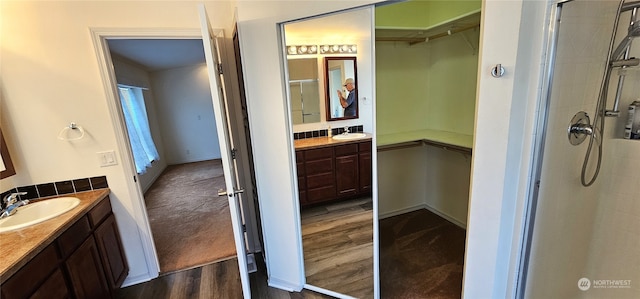 bathroom with walk in shower, vanity, and hardwood / wood-style floors