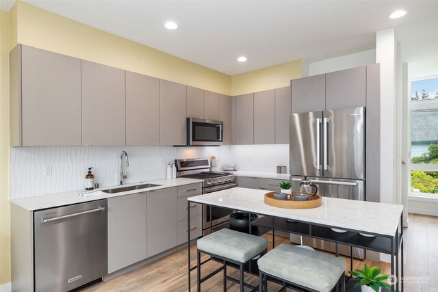 1325 NW 85th St, Seattle, WA 98117 - kitchen with sink, gray cabinets, light hardwood / wood-style floors, a kitchen bar, and stainless steel appliances