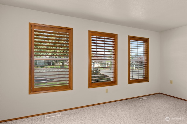 carpeted empty room featuring a textured ceiling