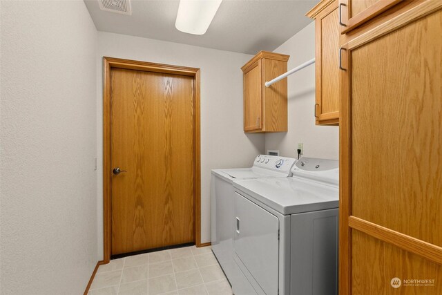 clothes washing area featuring cabinets and washing machine and clothes dryer