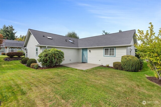 back of property with a lawn and a patio