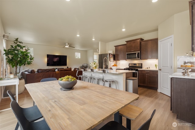 dining area with light wood-type flooring, ceiling fan, and sink