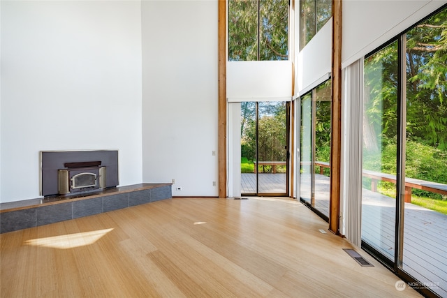 unfurnished living room with light wood-type flooring and a tiled fireplace