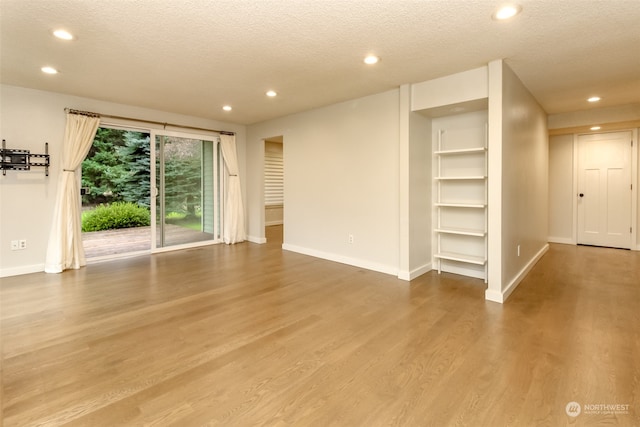 unfurnished living room with a textured ceiling and wood-type flooring