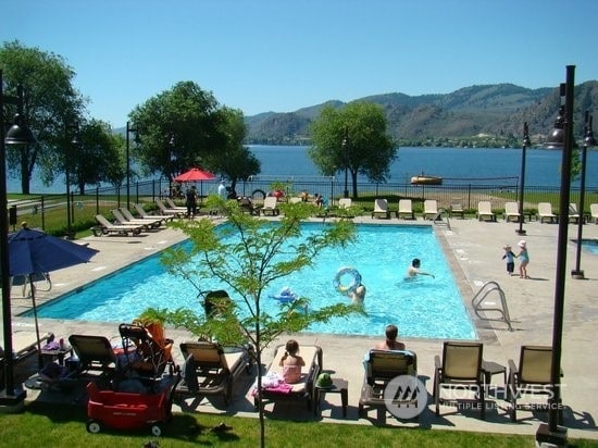 view of swimming pool featuring a water and mountain view and a patio