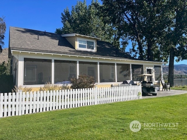 rear view of house featuring a lawn, a sunroom, and a patio area