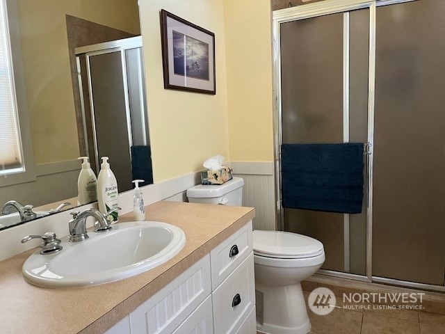 bathroom featuring vanity, a shower with shower door, toilet, and tile patterned floors