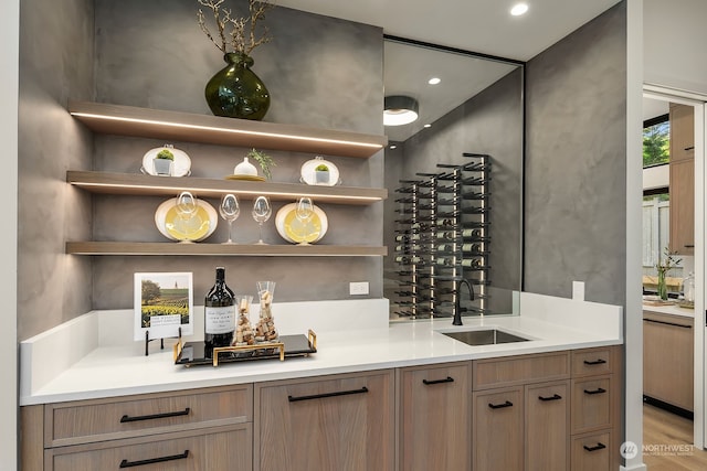 bar with light hardwood / wood-style floors and sink