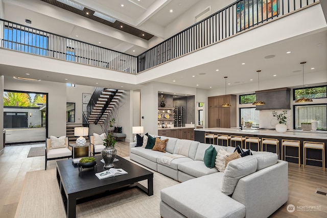 living room with light hardwood / wood-style flooring, a towering ceiling, and sink