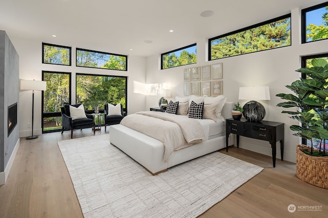 bedroom with light wood-type flooring and a high ceiling