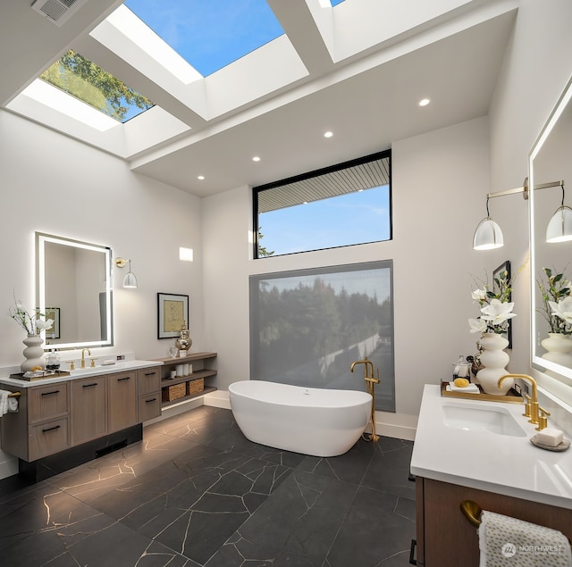 bathroom with a bath, vanity, a towering ceiling, and a skylight