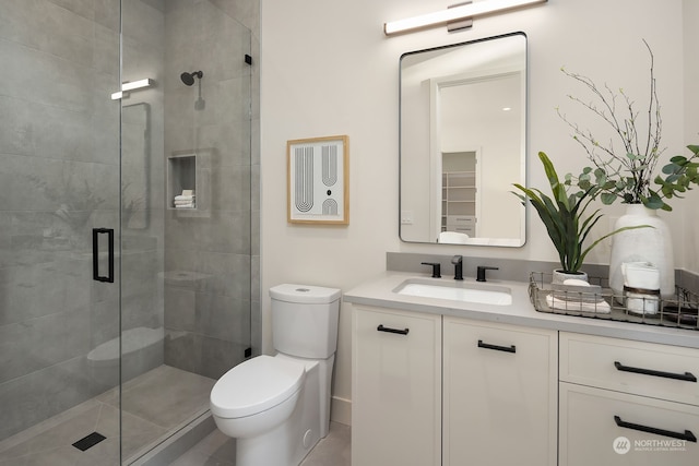 bathroom featuring tile patterned floors, walk in shower, vanity, and toilet