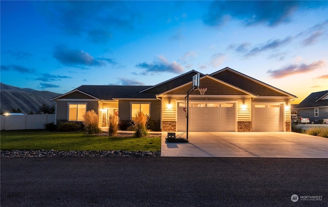 view of front of home featuring a front lawn, fence, a garage, stone siding, and driveway