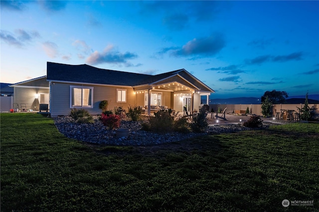 back of property at dusk featuring a yard, a patio area, and fence