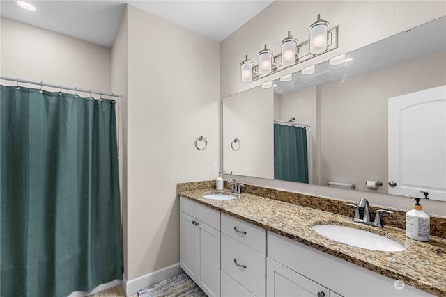 full bath with double vanity, baseboards, and a sink