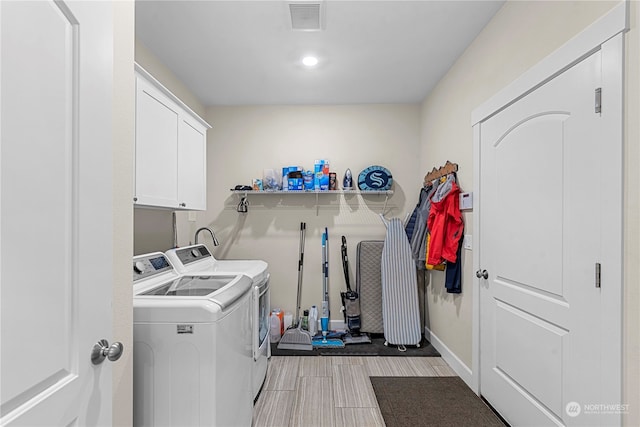 laundry area with baseboards, visible vents, wood finish floors, separate washer and dryer, and cabinet space