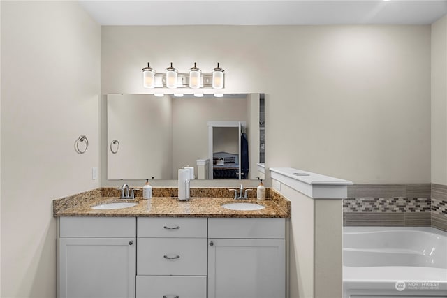 bathroom with double vanity, a garden tub, and a sink