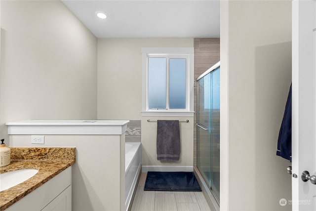 bathroom with a stall shower, vanity, and a bath