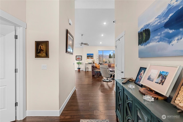 hall featuring recessed lighting, baseboards, dark wood-style floors, and a towering ceiling