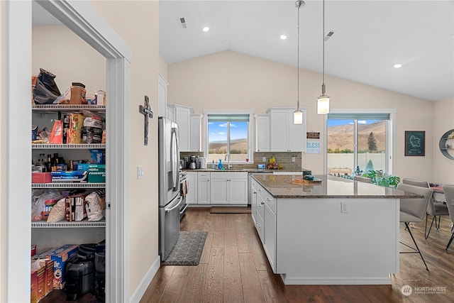 kitchen featuring a kitchen island, lofted ceiling, stainless steel refrigerator with ice dispenser, white cabinetry, and dark wood-style flooring