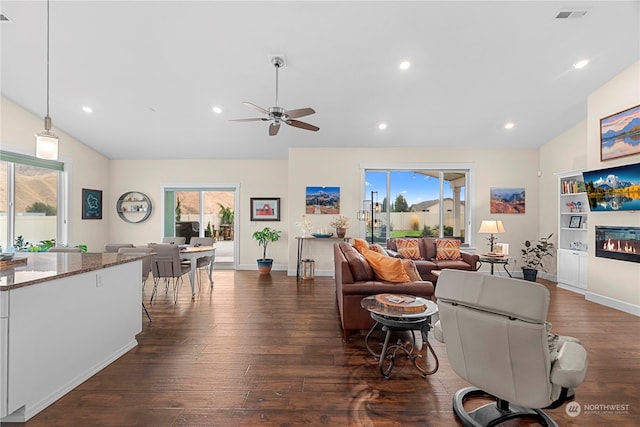 living room featuring recessed lighting, dark wood-type flooring, a glass covered fireplace, and vaulted ceiling