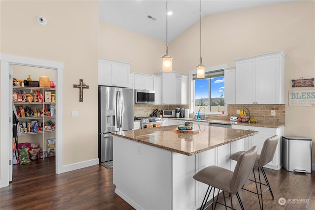 kitchen featuring a sink, a center island, light stone counters, stainless steel appliances, and dark wood-style flooring