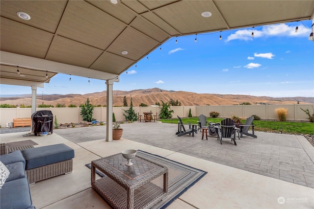 view of patio with an outdoor living space, a mountain view, and a fenced backyard